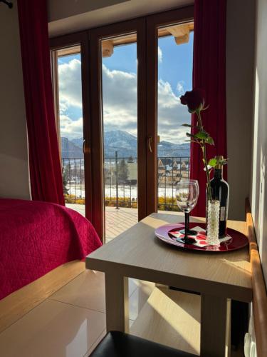 a room with a table with a glass of wine and a window at Willa Chrycówka - Jacuzzi, Basen, Sauna in Kościelisko