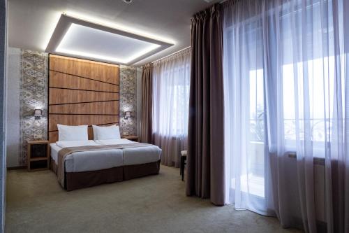 a hotel room with a bed and a large window at SPA Hotel Olymp in Velingrad