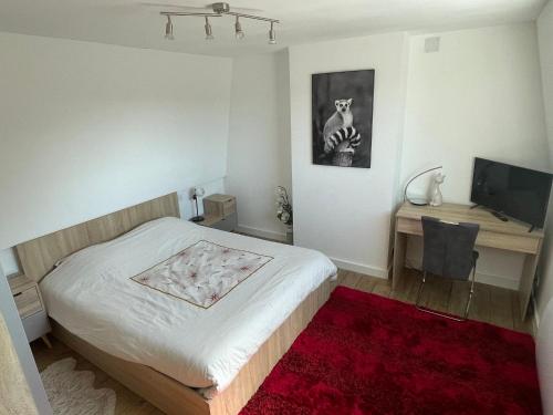 a bedroom with a bed and a desk with a television at L havre de paix in Avelin