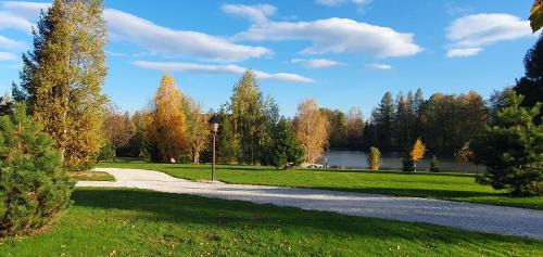 a path through a park with a lake and trees at Radhošťský rybník in Trojanovice