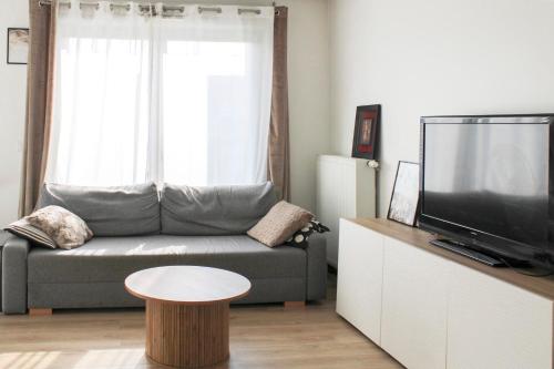un salon avec un canapé, une table et une télévision dans l'établissement T3 apartment with Wifi near Paris, à Bobigny