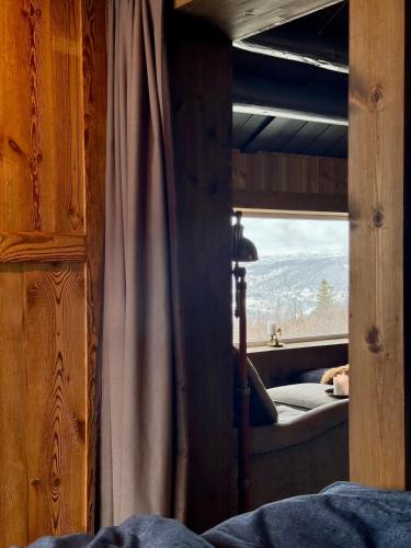 a bedroom with a bed and a window with a view at Geilo - Charming cottage with a stunning view in Geilo