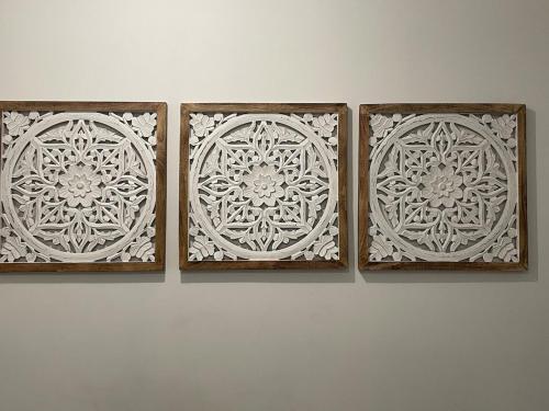 three wooden frames with white designs on a wall at Studio CLIMATISÉ au cœur de la ville, gare à pied, café offert in Castelnaudary