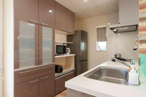 a kitchen with a sink and a stainless steel refrigerator at USJ電車1分 最大12名 一戸建て貸切 無料駐車2台可 ファミリー 団体最適 WiFi完備 in Osaka