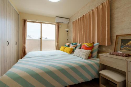 a bedroom with a striped bed with a window at USJ電車1分 最大12名 一戸建て貸切 無料駐車2台可 ファミリー 団体最適 WiFi完備 in Osaka