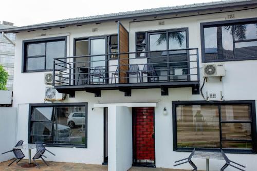 a white house with a red door and black windows at Vetho 1 Apartments OR Tambo Airport in Johannesburg