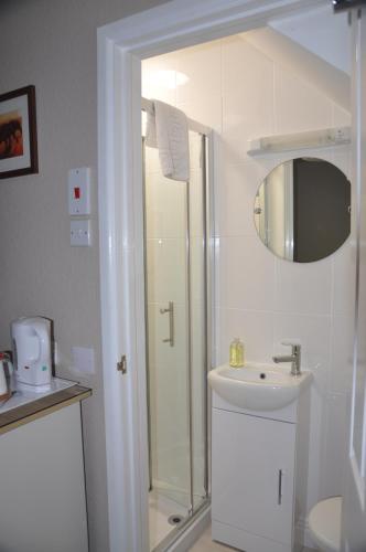 a white bathroom with a shower and a sink at Hotel Peppers in Torquay