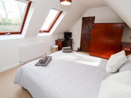 a bedroom with a large white bed in a attic at Old Stable Cottage in Alnmouth