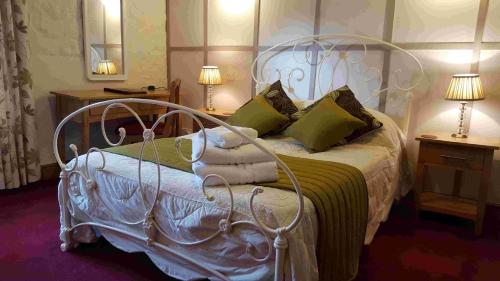 a bedroom with a white bed with green pillows at OYO The Walnut Tree in West Camel