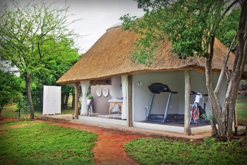 a thatch roofed house with a bicycle parked outside at Itaga Luxury Private Game Lodge in Bela-Bela