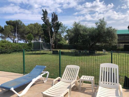3 chaises blanches et un fauteuil inclinable bleu sur une terrasse dans l'établissement Duplex 5 min de la mer, piscine, à Antibes