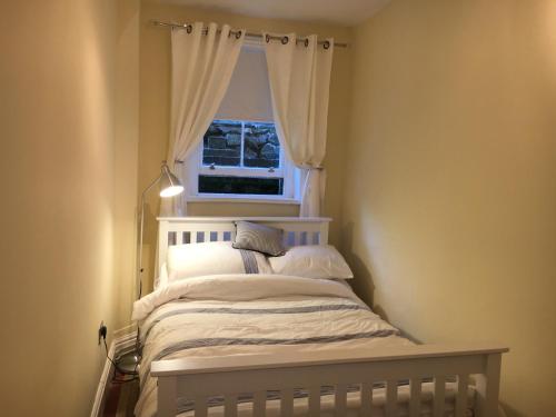 a bedroom with a white bed with a window at Garden View in Great Malvern