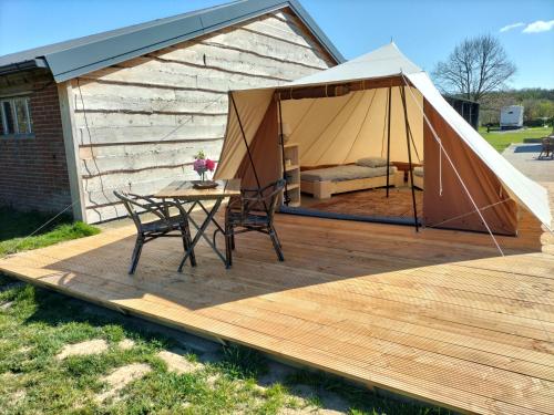a gazebo with a table and chairs on a wooden deck at Hoeve Linnerveld Trekkerstent in Sint Odiliënberg