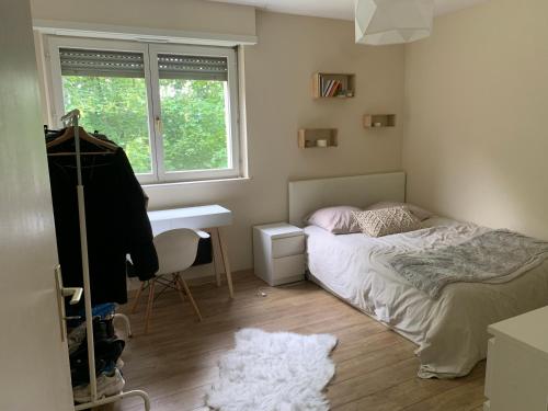 une chambre avec un lit, un bureau et une fenêtre dans l'établissement Lipsheim Proche gare, à Lipsheim