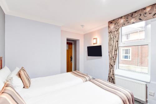 a white bedroom with a bed and a window at Aston Court Derby City Centre by Belvilla in Derby