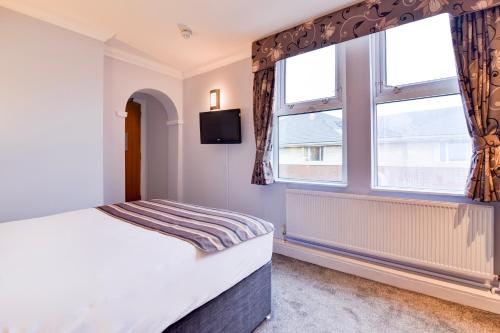 a bedroom with a bed and two windows at Aston Court Derby City Centre by Belvilla in Derby