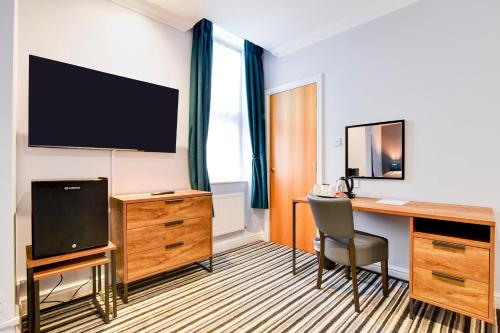 a hotel room with a desk and a television at Aston Court Derby City Centre by Belvilla in Derby