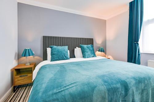 a bedroom with a large blue bed with blue pillows at Aston Court Derby City Centre by Belvilla in Derby