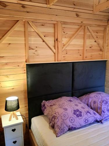 a bed with a black headboard and a purple pillow at Domki na Kociewiu Pati in Skarszewy