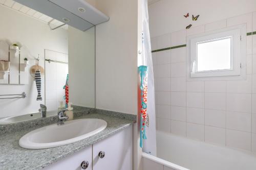 La salle de bains blanche est pourvue d'un lavabo et d'une baignoire. dans l'établissement Le Victoria - Proche de la Plage, à Saint-Jean-de-Monts