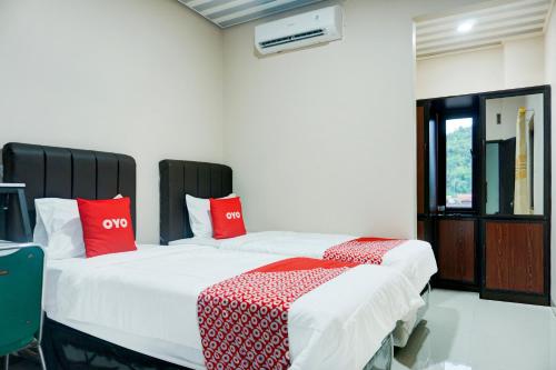 バンダールランプンにあるHotel O Kedaton Near Rumah Sakit Advent Bandar Lampung Formerly Hotel Plain C Lakeの赤い枕が備わる客室内のベッド2台
