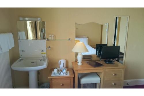a bathroom with a sink and a desk with a computer at The Belgrave Hotel Tenby in Tenby