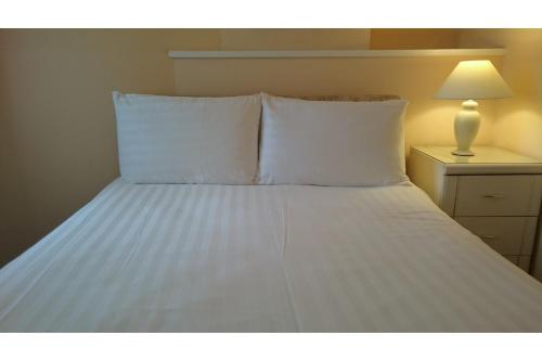 a bed with white sheets and pillows in a room at The Belgrave Hotel Tenby in Tenby