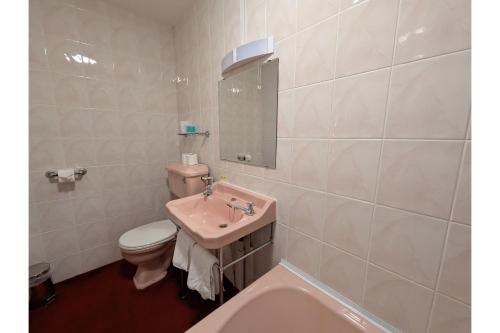 a bathroom with a sink and a toilet and a tub at The Belgrave Hotel Tenby in Tenby