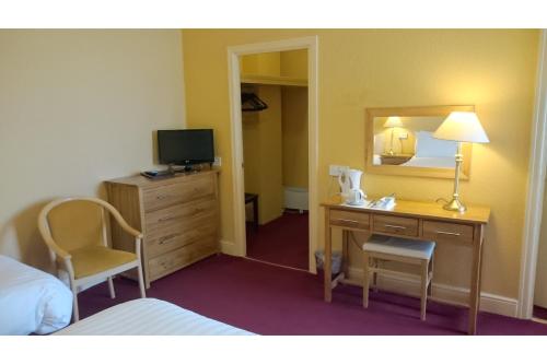 a hotel room with a desk and a mirror at The Belgrave Hotel Tenby in Tenby