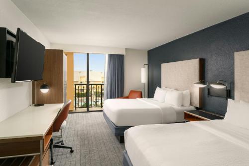 a hotel room with two beds and a desk at Courtyard by Marriott Boynton Beach in Boynton Beach