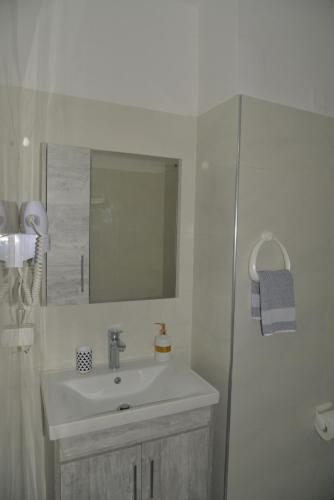 a white bathroom with a sink and a mirror at Tonia Apartments Kontogialos in Pelekas