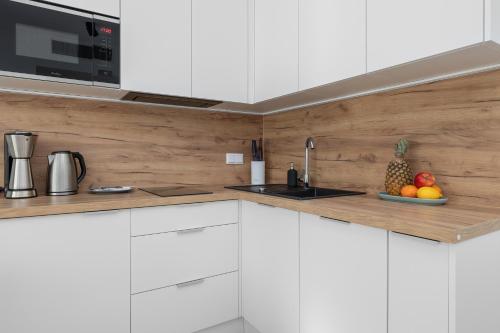 a kitchen with white cabinets and a bowl of fruit at Apartament Relax Rogowo Balkon & Parking by Noclegi Renters in Rogowo