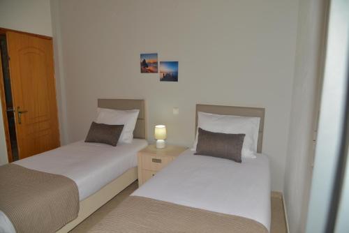 two beds in a bedroom with a candle on a night stand at Tonia Apartments Kontogialos in Pelekas
