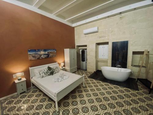a large bathroom with a tub and a bed and a bath tub at Ta' Tereża Farmhouse in Xagħra