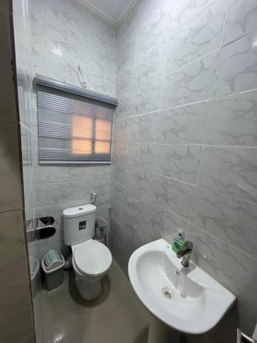 a white bathroom with a toilet and a sink at Feathers Apartments Abuja in Abuja