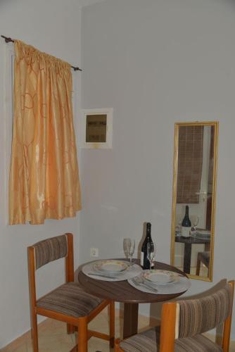 a dining room table with two chairs and a mirror at Tonia Apartments Kontogialos in Pelekas