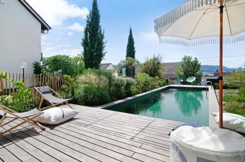 a swimming pool with two chairs and an umbrella at SeeSucht-Apartment No86 mit Terrassen, Sauna & Pool in Bodman-Ludwigshafen