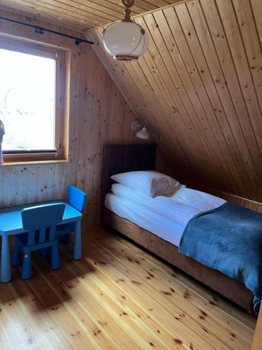 a bedroom with a bed and a table in a room at Domek całoroczny HAWAJE nad jeziorem Kazub in Cieciorka