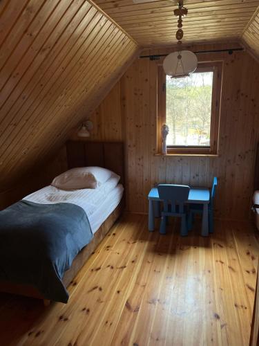 a bedroom with a bed and a table in a attic at Domek całoroczny HAWAJE nad jeziorem Kazub in Cieciorka