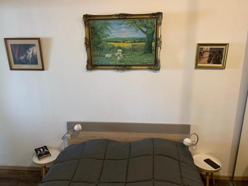 une chambre avec un lit et un tableau au mur dans l'établissement Le Petit Breizh, gîtes culturel Aux Petits Bonheur, à Férel