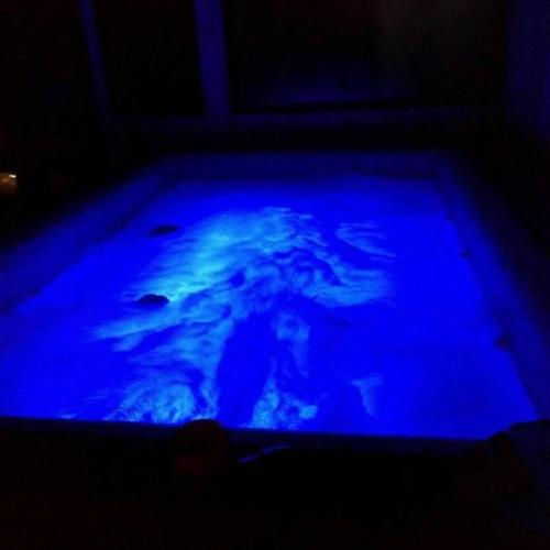 a blue pool of water with a person in it at Cabana Elena - Private SPA in Brădetu
