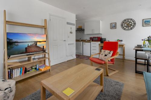 a living room with a red chair and a table at Our Happy Place- With Parking & Upgraded WiFi for 2025 in Brixham