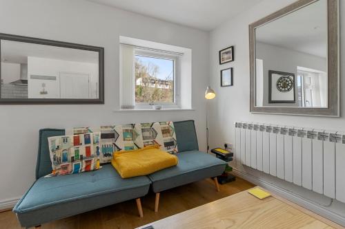 a living room with a blue couch and a mirror at Our Happy Place- With Parking & Upgraded WiFi for 2025 in Brixham