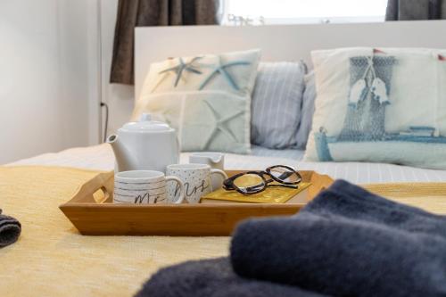 a tray with glasses and cups on a bed at Our Happy Place- With Parking & Upgraded WiFi for 2025 in Brixham