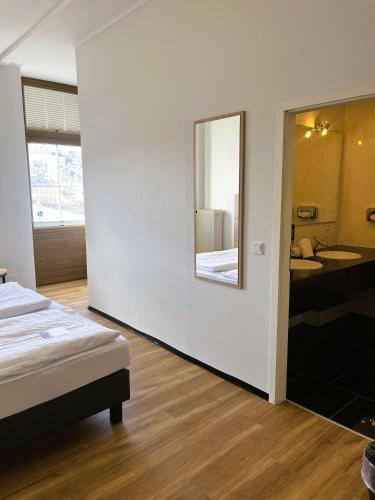 a bedroom with a bed and a mirror and a bathroom at Moselhotel Römischer Kaiser in Bernkastel-Kues