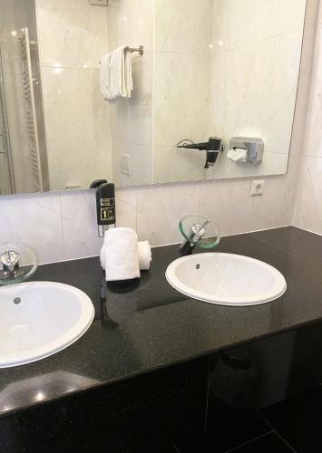 a bathroom with two sinks and a mirror at Moselhotel Römischer Kaiser in Bernkastel-Kues
