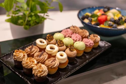 a tray of cupcakes on a table with a bowl of fruit at Brussels Marriott Hotel Grand Place in Brussels