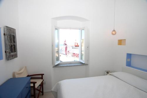 a white bedroom with a bed and a window at Occhio sul mare in Isola del Giglio