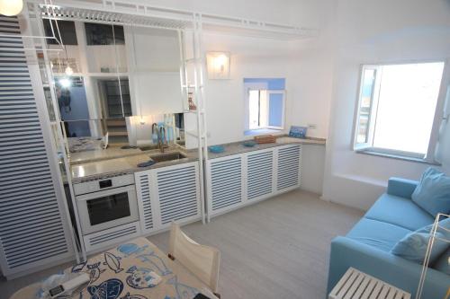 a living room with a blue couch and a kitchen at Occhio sul mare in Isola del Giglio