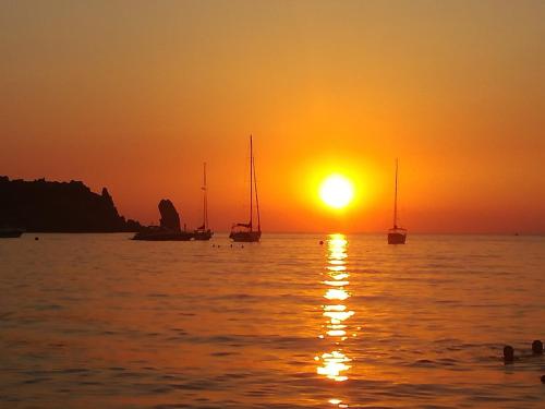a sunset over the ocean with boats in the water at Occhio sul mare in Isola del Giglio